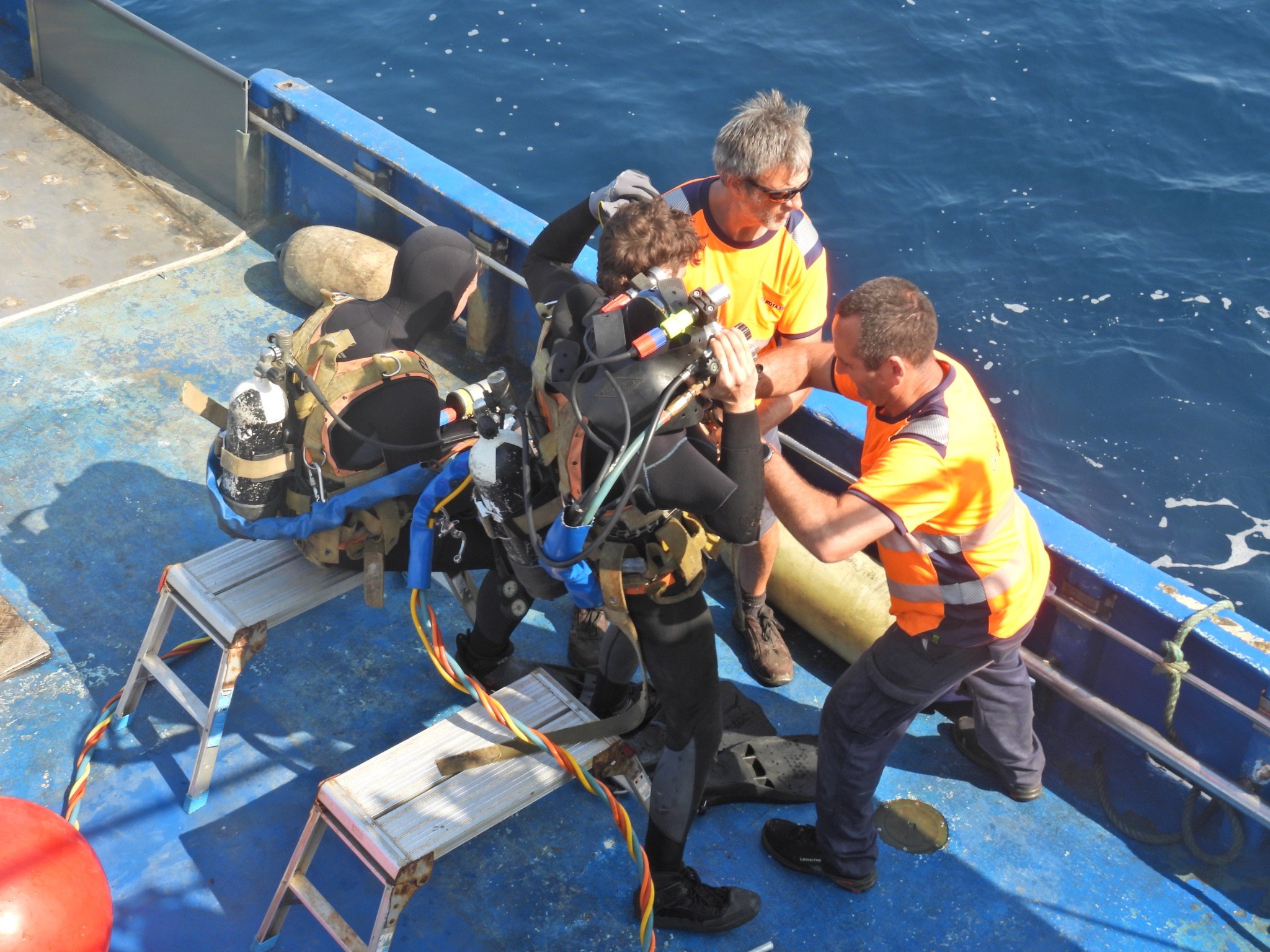 Divers and offshore crew preparing equipment on board a vessel during installation and monitoring works.